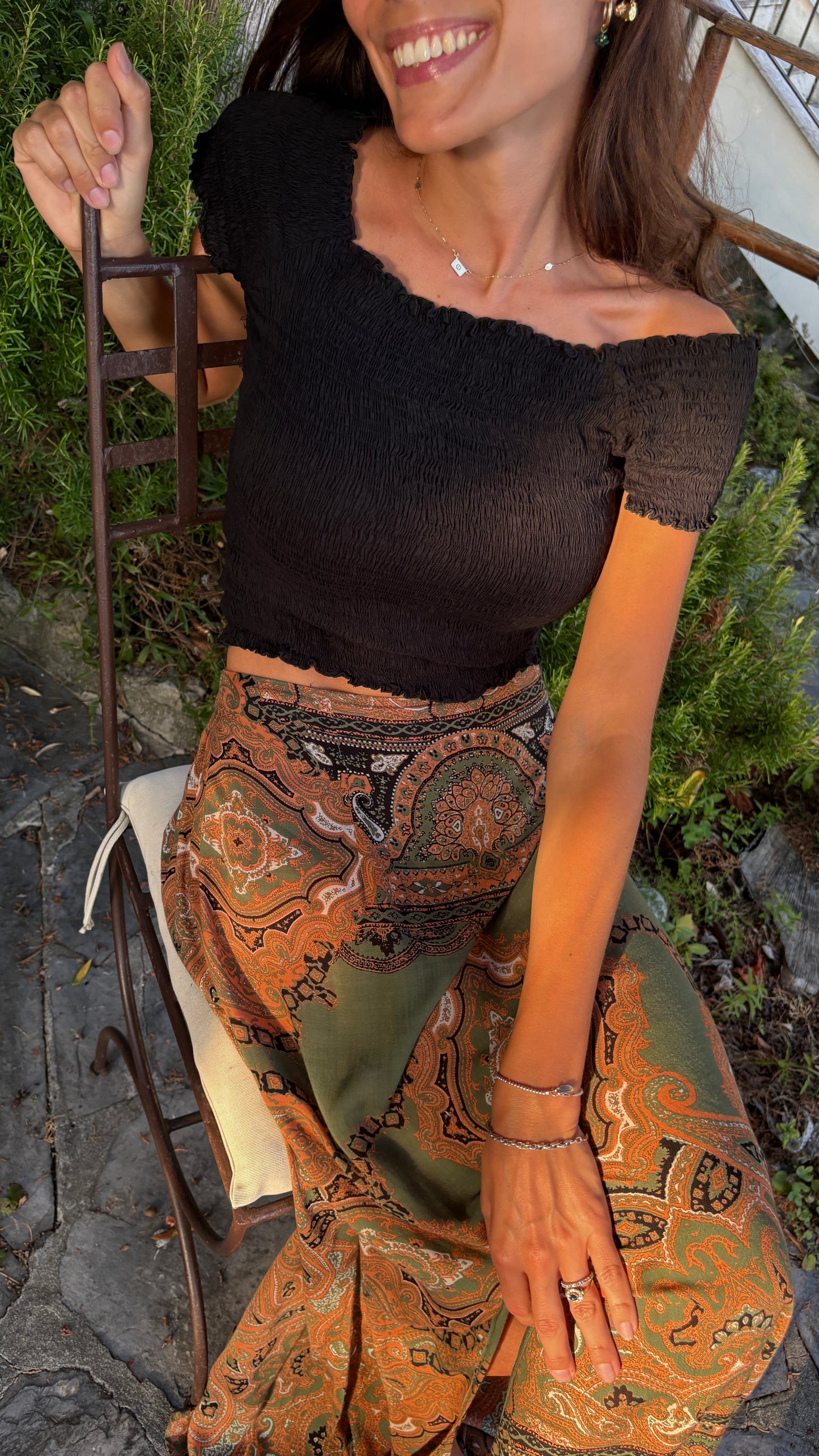 gonna lunga leggera stampa paisley verde nera arancione ideale primavera estate quando fa caldo con top nero da donna sorridente seduta in giardino di lusso stile resortwear lifestyle lapeapois